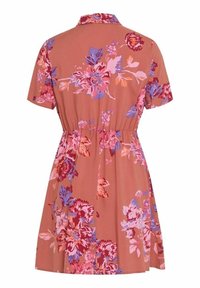 Kurzärmliges, knielanges Kleid mit kragenähnlichem Ausschnitt, elastischem Taillenbund und großem blühendem Muster in Pink, Lila und Rot auf terrakottafarbenem Hintergrund.