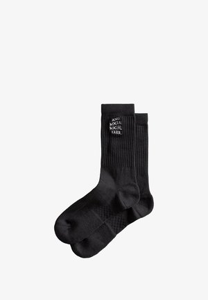 Czarne skarpetki crew z ribbowanym wzorem i białym logo "ANTI SOCIAL SOCIAL CLUB" na mankiecie. Gładka tkanina.