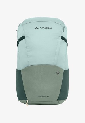 Sac à dos bleu clair avec des accents gris. Présente une texture lisse, un haut zippé et des bretelles réglables. Étiquette "Skomer Zip 22" visible.