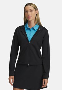 Black zip-up hoodie with a hood, made from smooth material, paired with a blue collared shirt. Smooth texture and fitted design.
