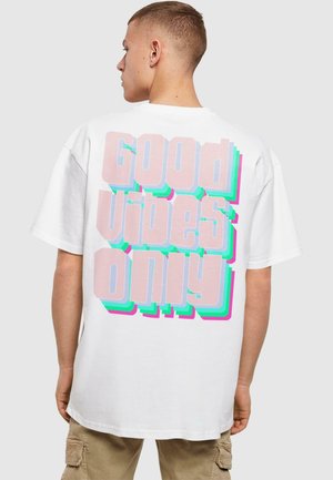 Hvid bomuld t-shirt med en stor, multifarvet grafisk tekst "Good Vibes Only" i fede, lagdelte skrifttyper på bagsiden.