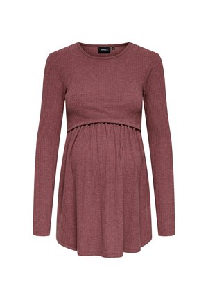 Haut de maternité à manches longues en rose profond, texture côtelée, avec un corps ajusté et un ourlet évasé, conçu pour le confort et le style pendant la grossesse.