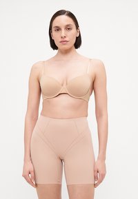 Beige beha met gladde cups en dunne verstelbare bandjes, gecombineerd met hooggesneden, huidskleurige shapewear met geperforeerde details.