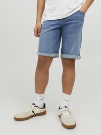 Ljusblå denimshorts med upprullade kantar, med framfickor. Matchas med beige sneakers och vita strumpor med en subtil design.
