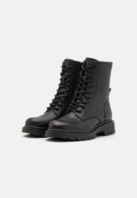 Black leather ankle boots with a textured finish, featuring a lace-up front and a rugged, grooved sole for traction.
