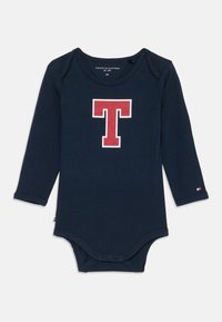 Sötétkék, hosszú ujjú babaruha piros és fehér "T" betűvel a mellkason, három patentes alján, és Tommy Hilfiger logóval az ujján.