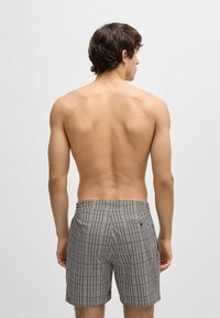 Patroon zwemboxers met een geometrisch ontwerp, voorzien van een tailleband en achterzakken. Kleuren zijn marineblauw en wit.