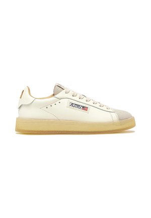 Zapatilla blanca de cuero de perfil bajo con puntera de ante beige, suela beige y parche con el logo de Autry que presenta una bandera estadounidense en el lateral.