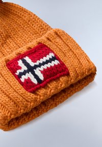 Pletená oranžová čepice s červenou nášivkou s bílým a tmavě modrým designem norské vlajky. Textura je silná a teplá.