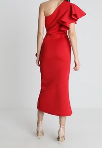 Vestito midi rosso con una spalla, dettaglio a volant, silhouette aderente e orlo asimmetrico. Tessuto liscio con una finitura strutturata.