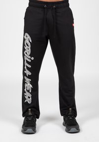Zwarte sweatpants met een relaxte pasvorm, elastische tailleband en trekkoord; voorzien van een grote zilveren grafische print op een been; slanker textuur.