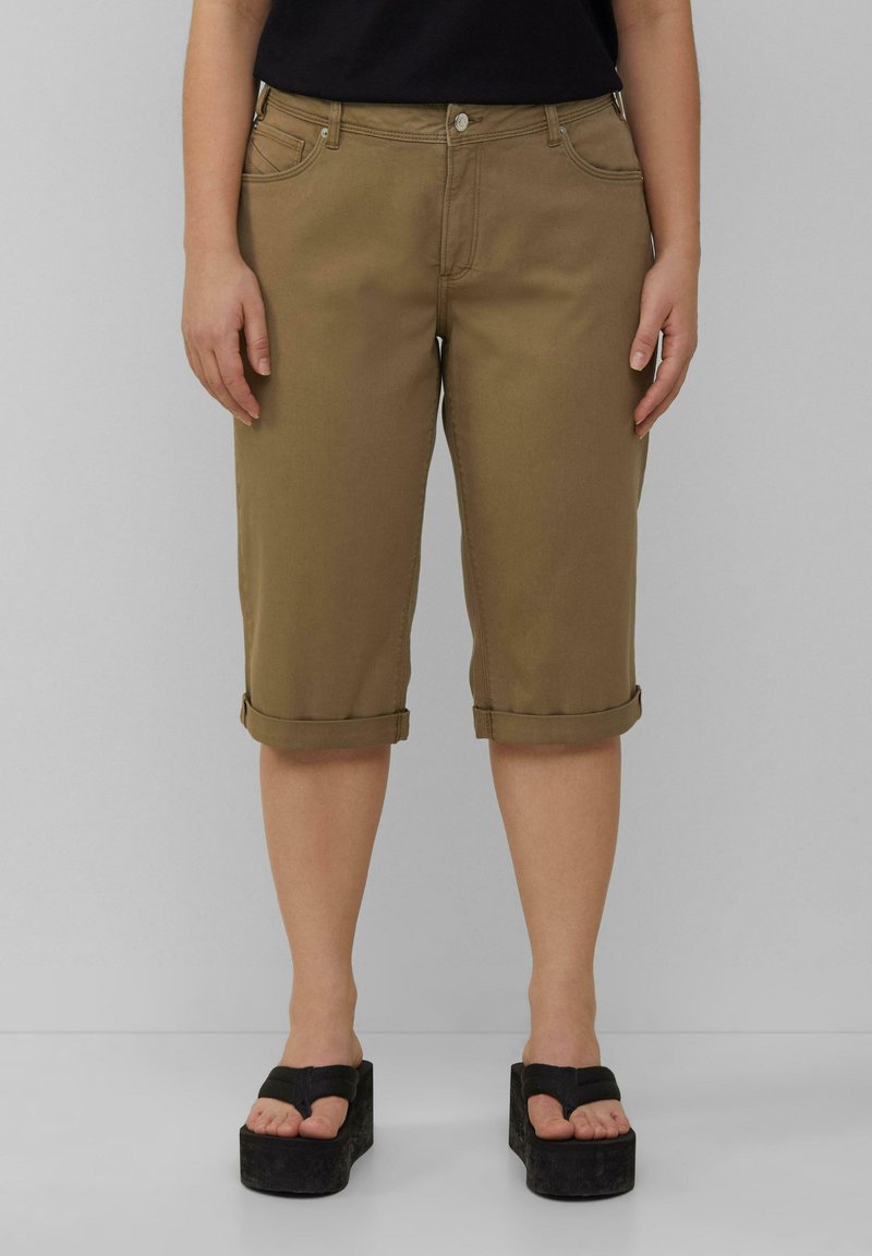 Bruine cargo pantalons tot de knie met een opgerold uiteinde, voorzakken en een knoopsluiting, gecombineerd met zwarte platform sandalen.