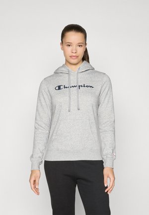 Grå hettegenser med frontlomme, snorer og Champion-logo i mørkeblått. Ribbestrikkede mansjetter og nederkant med børstet tekstur.