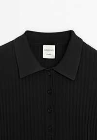 Polo noir côtelé avec col et quatre boutons sur le devant, étiqueté "Massimo Dutti Studio".