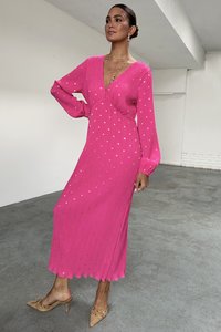 Pink long-sleeve dress with a V-neck, featuring a ribbed texture and gold dot patterns. The dress has a flared hem and is ankle-length.
