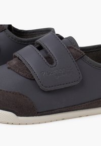 Scarpe grigie scure con una tomaia in pelle liscia e dettagli in suede scuro. Presentano una fascia in Velcro e una suola in gomma testurizzata per una buona aderenza.