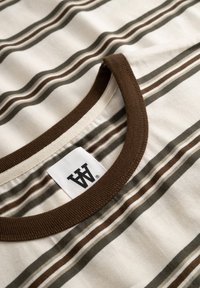 T-shirt en coton rayé présentant des lignes horizontales crème, vertes et marron. Col en côtes marron contrastant et étiquette tissée visible.