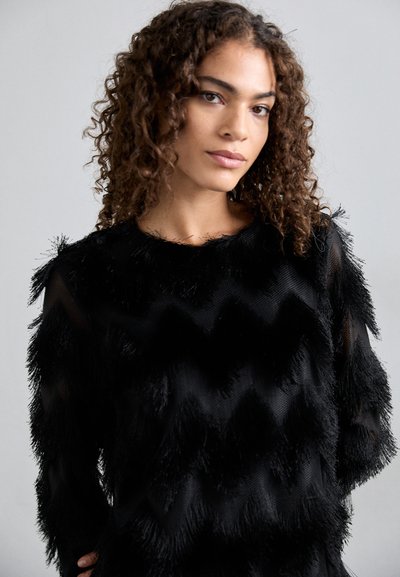 Μαύρο πουλόβερ με υφή, που διαθέτει μοτίβο ζιγκ-ζαγκ και λεπτομέρειες με κρόσσια. Κατασκευασμένο από μαλακ�ό ύφασμα με λαιμόκοψη crew και μακριά μανίκια.