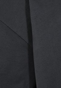 Mørkegrå stof med en glat tekstur, der har overlapende paneler og et subtilt, ensartet mønster. Kompositionen er minimalistisk og moderne.
