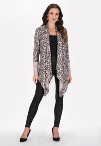Cardigan cu imprimeu leopard dintr-o țesătură moale, având un design deschis în față, hem drapat și mâneci lungi, purtat cu colanți negri ajustați și toc.