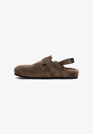 Scarpa slip-on in suede marrone con superficie texturizzata, schiena aperta, doppie cinghie e suola in gomma. Presenta una morbida fodera in pelliccia per il comfort.