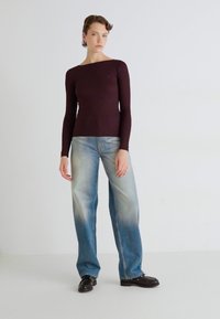 Maglietta a maniche lunghe color bordeaux abbinata a jeans dritti chiari e sbiaditi. Scarpe nere completano l'outfit informale. Design pulito e minimale.