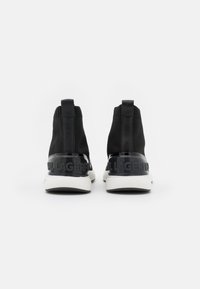 Sneaker alte nere con tomaia in maglia testurizzata, dettagli in vernice nera lucida e suole bianche con logo sul tallone.