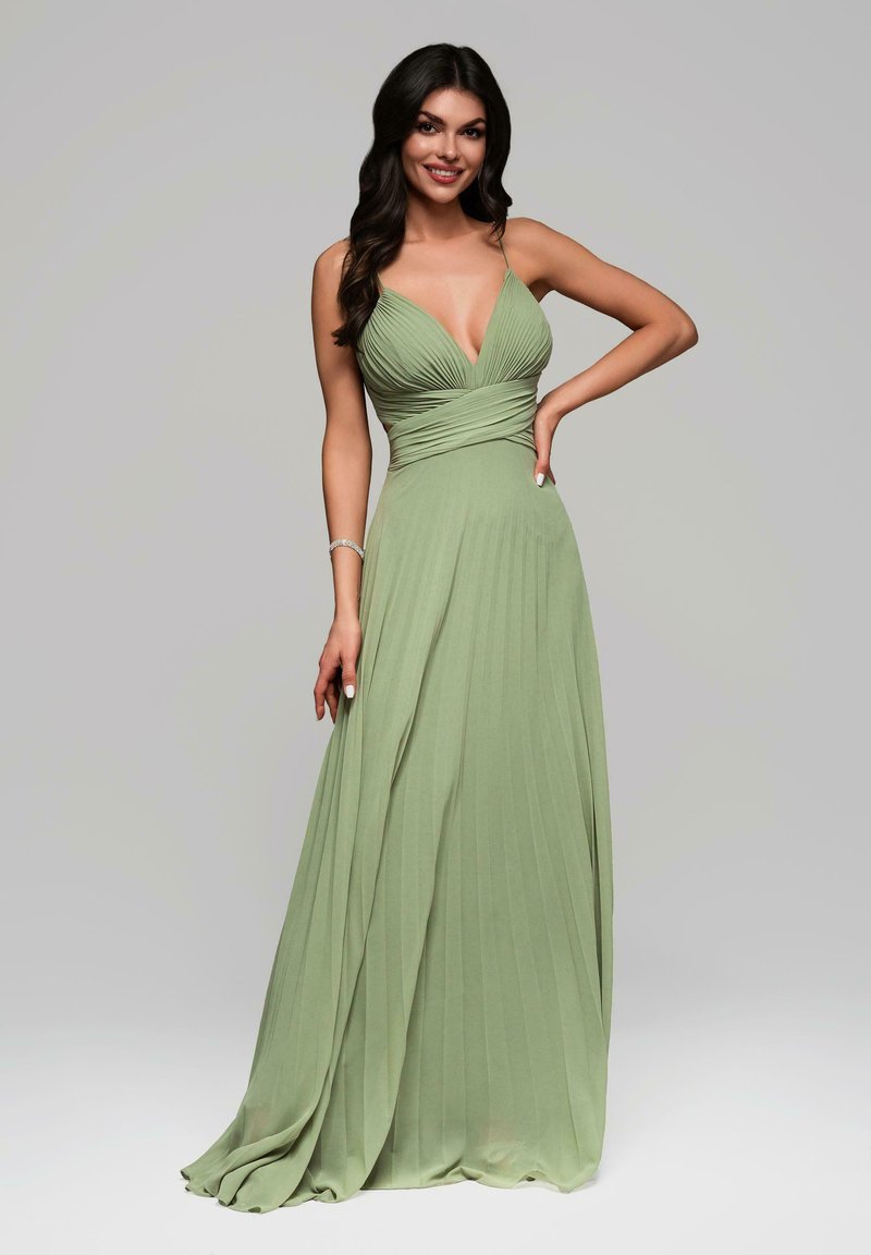Robe plissée verte avec un décolleté en V plongeant et des fines bretelles, présentant un corsage ajusté et une jupe fluide. Tissu lisse et léger.