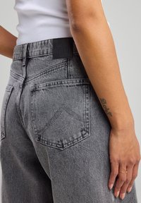Gray denim jeans featuring a high waist, stitched back pockets, and a black leather label with "AMERICA TODAY" embossed on the waistband.