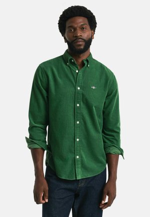 Groene corduroy overhemd met een knoopsluiting kraag, met lange mouwen en een klein logo op de borst. Draagt het met donkere spijkerbroek.