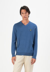 Maglione blu a V in tessuto lavorato a maglia con maniche lunghe e rifiniture a costine, dotato di un piccolo logo giallo sul lato sinistro del petto.