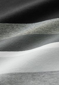 Tessuto di cotone con strisce orizzontali nere, grigie e bianche; texture liscia con dettagli di cucitura visibili in diverse tonalità.