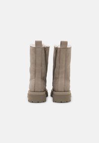 Beige enkellaarzen met een gestructureerde leren buitenkant, voorzien van een rits aan de zijkant, een zachte bontvoering en een stevige rubberen zool.