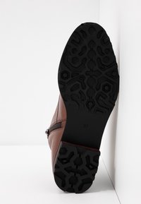 Bottine en cuir marron avec une semelle en caoutchouc noir texturé, présentant un motif en zigzag et une fermeture éclair sur le côté. Taille 37 indiquée sur la semelle.