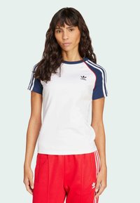 Vit kortärmad t-shirt med marinblå krage och ärmsömmar, med en liten svart Adidas-logotyp på bröstet. Slät tyg, avslappnad passform.