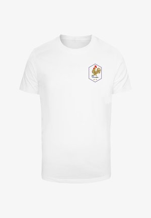T-shirt bianco in cotone con un emblema esagonale che presenta un gallo marrone e un pallone da calcio, decorato da due stelle sotto l'emblema.