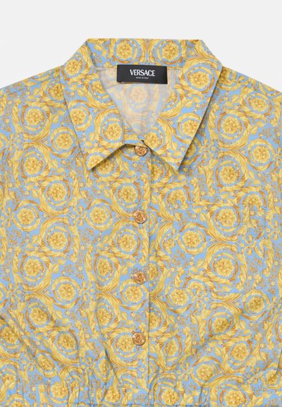 Blue floral shirt featuring yellow swirling patterns, a classic collar, and gold buttons along the front placket. Made by Versace.