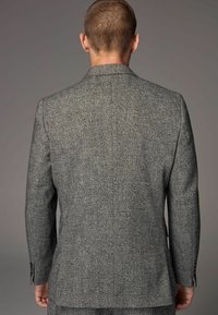 Grå houndstooth blazer med en struktureret vævning, strukturerede skuldre og dobbelte knaplukninger med manchetter ved håndleddene.