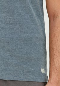T-shirt blu con effetto melangiato, colletto rotondo, maniche corte e superficie testurizzata. Presenta un piccolo logo sulla cucitura.