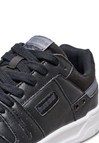 Czarne skórzane buty z szarymi tekstylnymi akcentami, okrągłym noskiem i teksturowaną powierzchnią. Posiadają czarne sznurowadła oraz naszywkę z logo na języku.