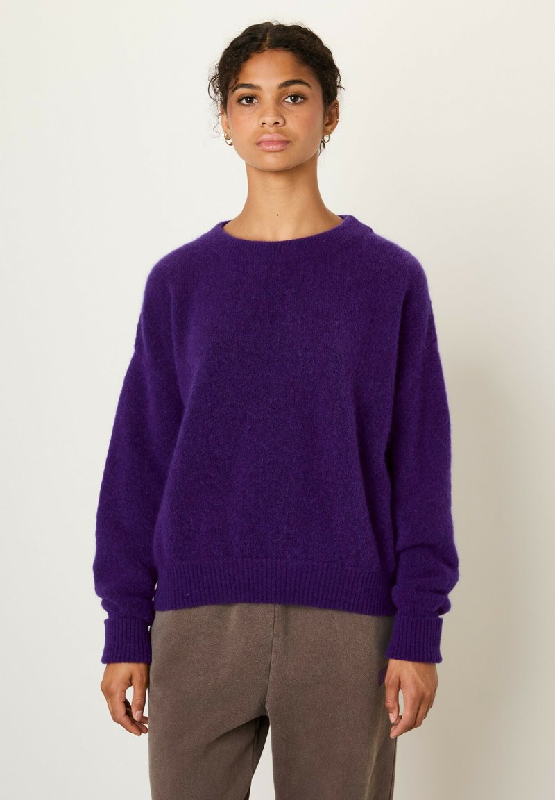 Maglione viola morbido con collo rotondo, polsini e orlo a costine. Il tessuto appare soffice e testurizzato, creando una vestibilità comoda.