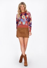 Maglione lavorato a maglia floreale colorato con maniche lunghe, abbinato a una gonnellina in suede marrone e stivaletti alla caviglia marroni, con un taglio unico.