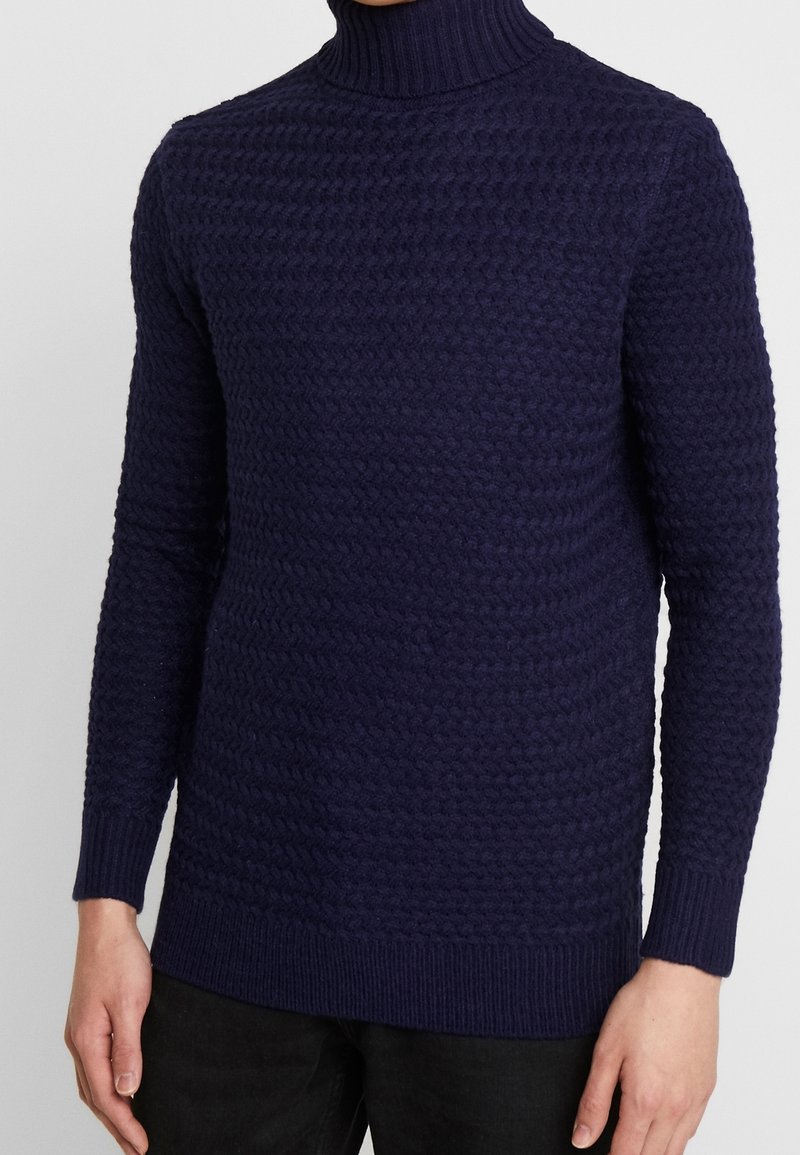 Granatowy sweter z golfem wykonany z dzianiny, z teksturowanym, wypukłym wzorem i długimi rękawami, z prążkowanymi mankietami i dołem, co zapewnia dopasowany wygląd.