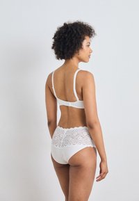 Witte lingerieset met een bh met dunne bandjes en haaksluiting, gecombineerd met hooggeknipte slips versierd met kantdetails.