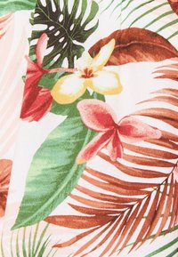 Tissu floral tropical présentant de grandes feuilles vertes, des fleurs roses et rouges, ainsi que des accents jaunes sur un fond clair, avec une surface texturée.