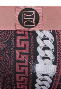 Tessuto stampato con un mix di design rosso e nero, caratterizzato da un elemento intrecciato spesso e una toppa con logo in rosa e nero.