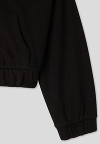 Felpa nera corta con un morbido misto cotone, polsini elasticizzati e una tasca laterale, dal texture liscia e con dettagli di cucitura minimi.