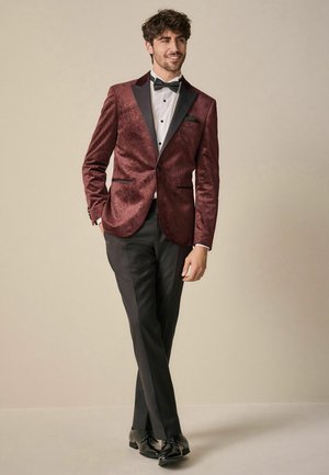 Burgundy patterned tuxedo jacket with black accents, white shirt, black bow tie, and black trousers, paired with shiny black shoes.