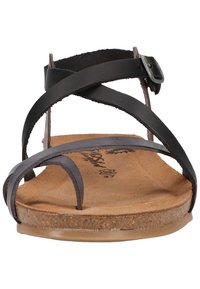Sandalo in pelle nera con cinturini incrociati, soletta in sughero e suola piatta. Presenta una chiusura con fibbia e una texture liscia.