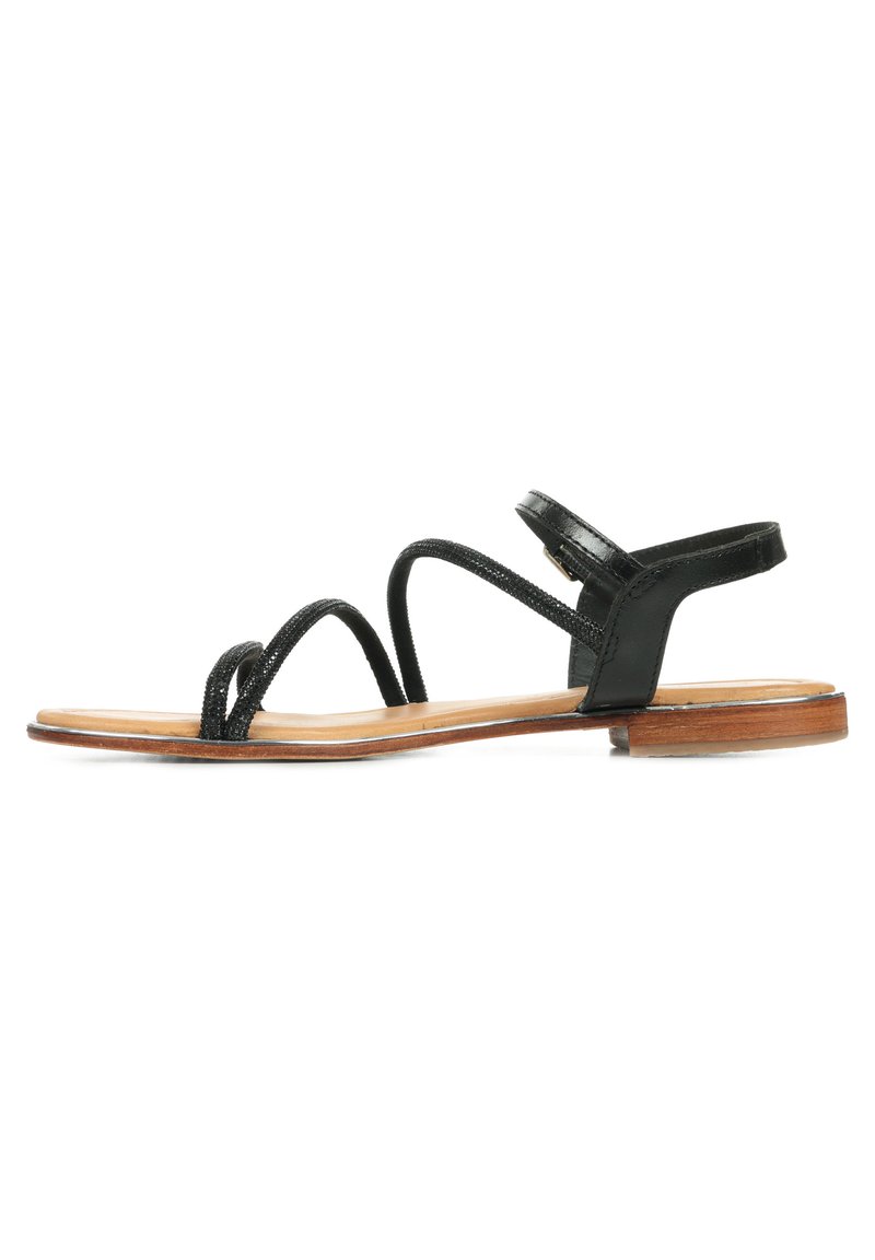 Sandali neri in pelle con cinturini sottili, suola piatta e chiusura con fibbia alla caviglia. Texture liscia con un design minimalista.